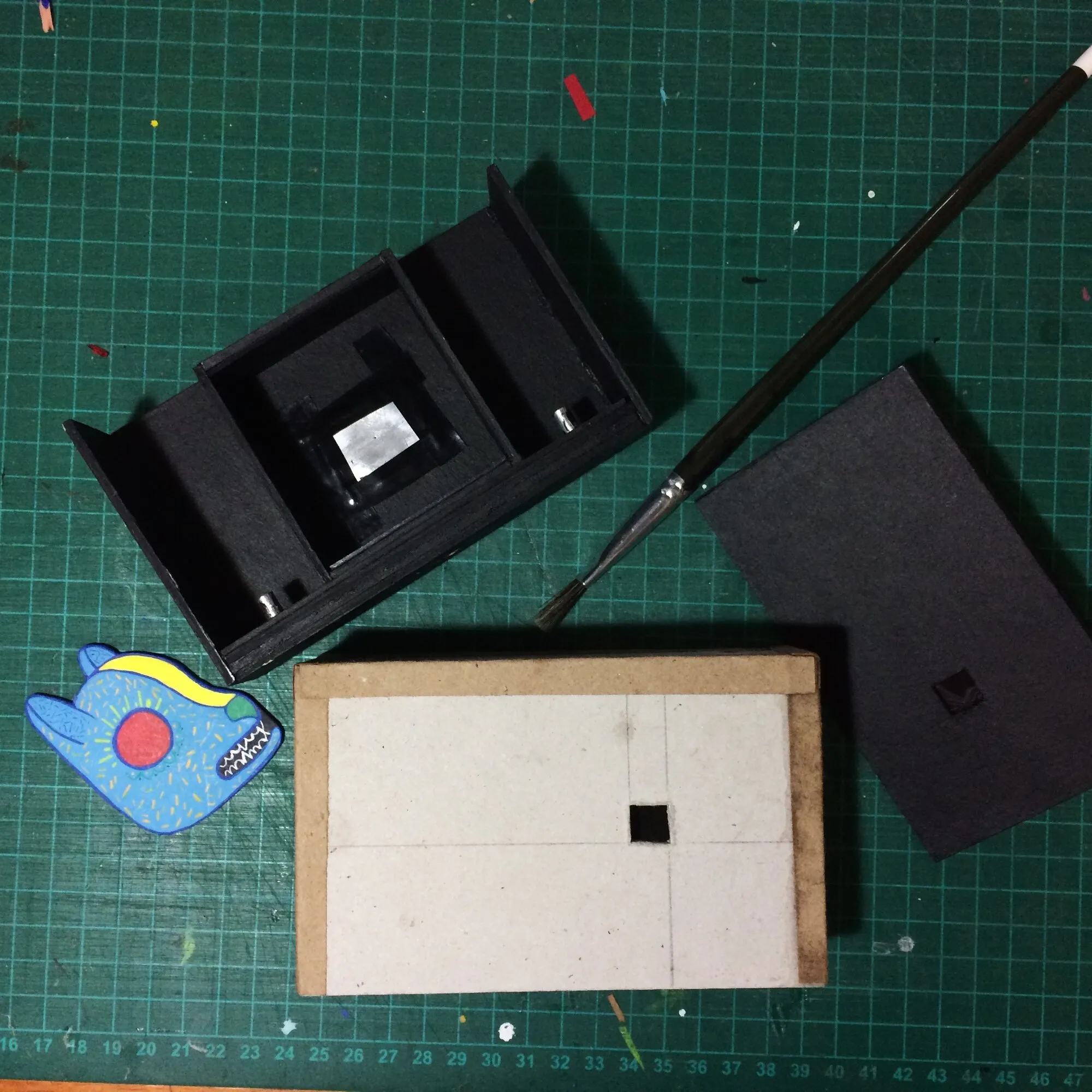 Piezas de la cámara sobre la tabla de corte: caja negra, tapa y el cuerpo interior blanco
