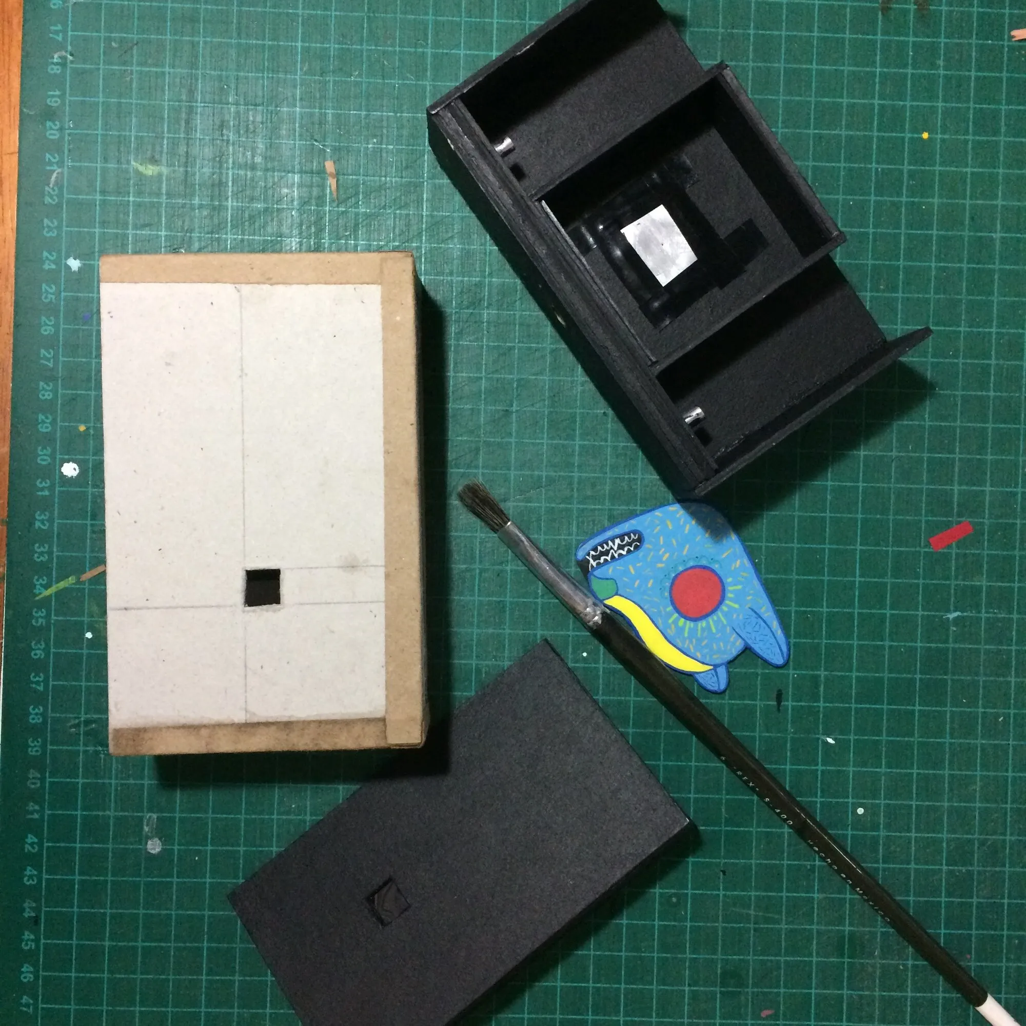 Caja de la cámara abierta junto al cuerpo interior y el alebrije recortado