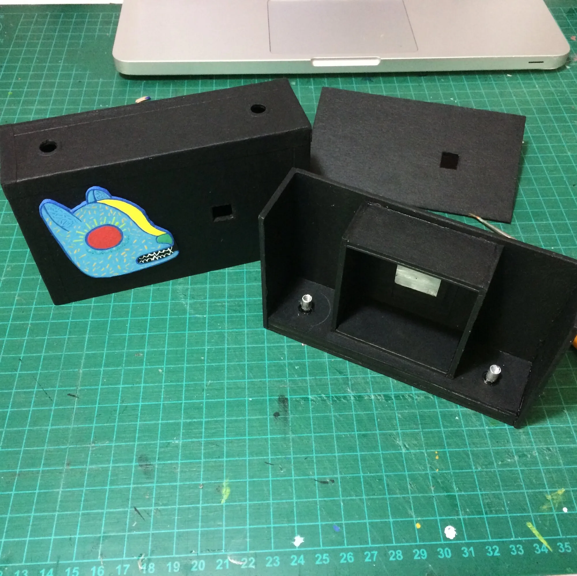 Caja de la cámara con el alebrije pegado y el cuerpo interior a un lado