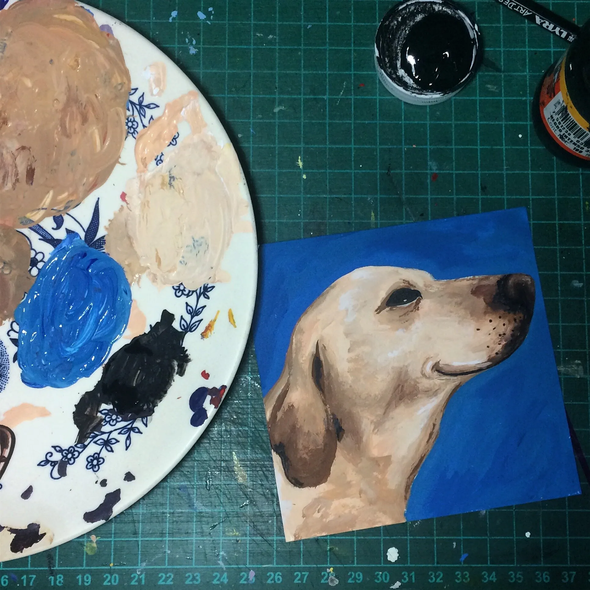 Paleta con acrílicos junto a la pintura del perro sobre la tabla de corte
